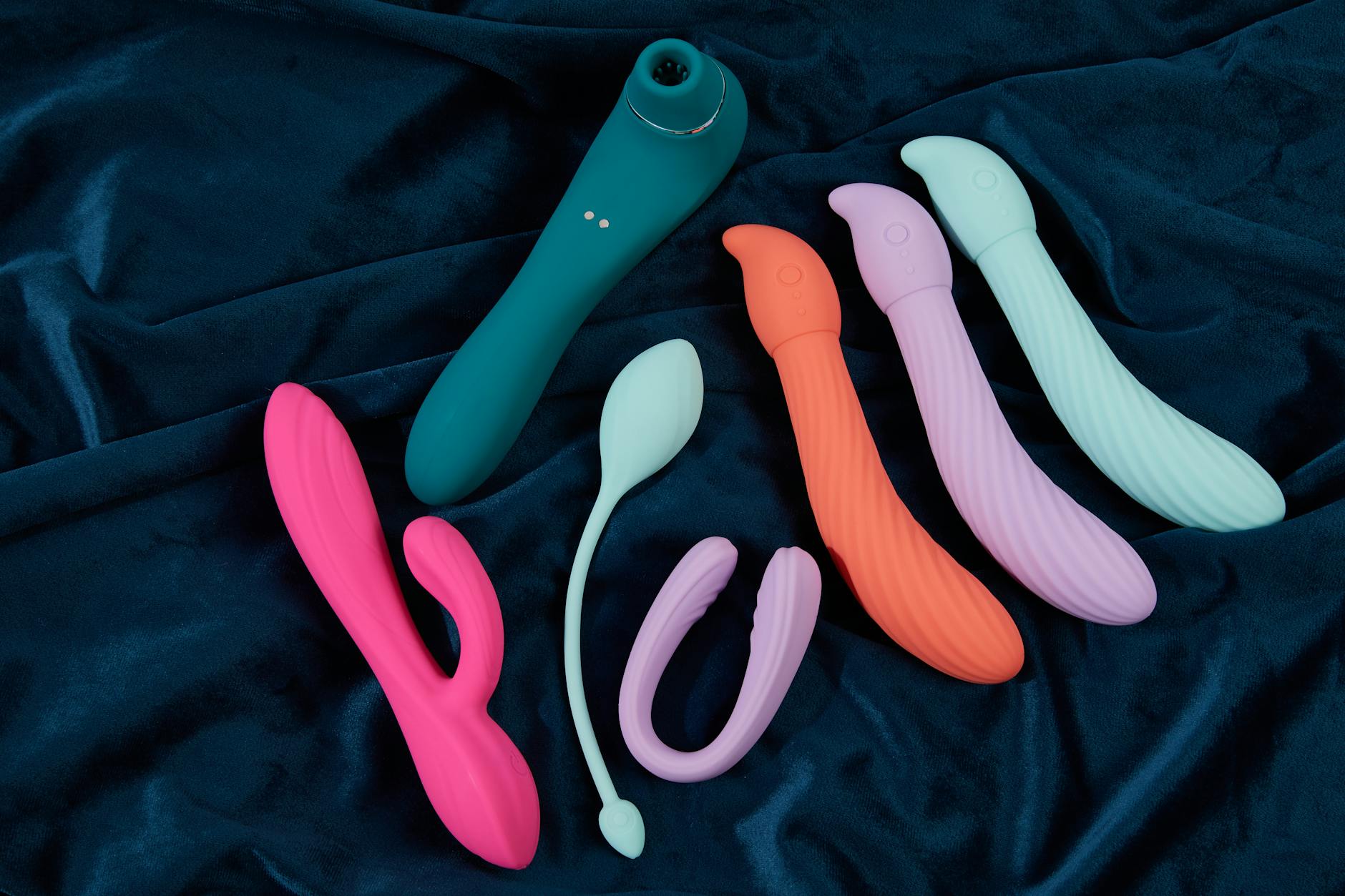Close-up of a blue silicone vibrator held gently in hand against a soft purple background