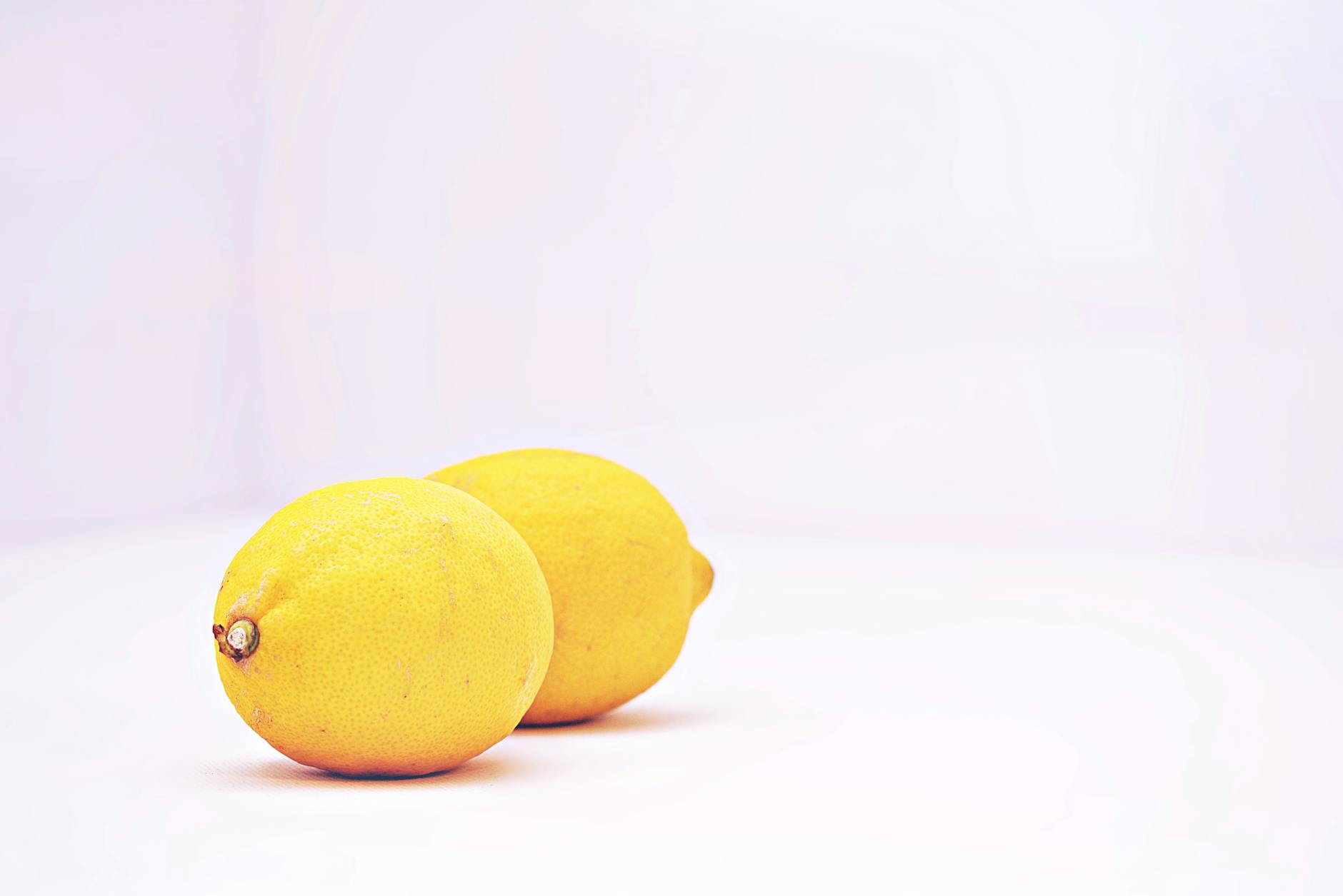 Two vibrant fresh lemons against a clean white background