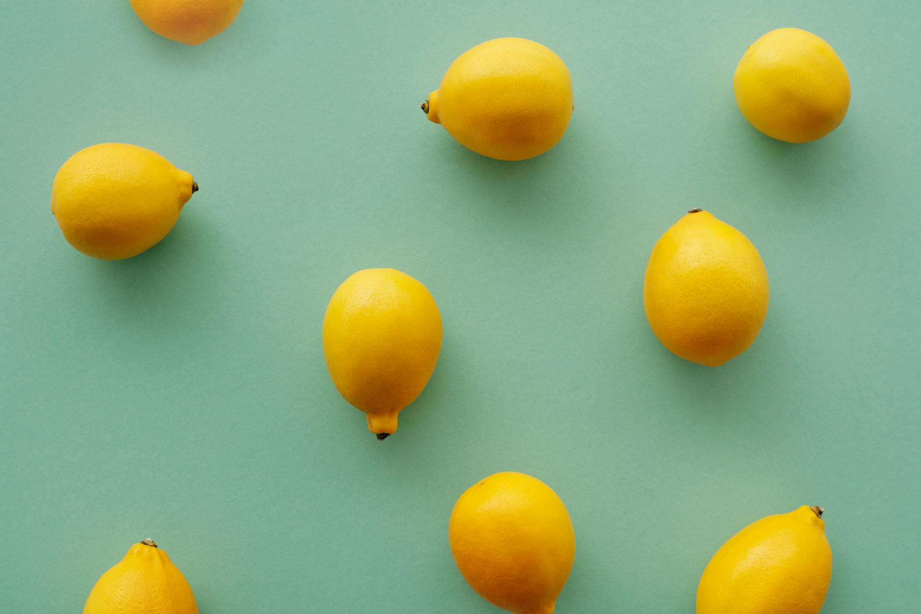 Bright yellow lemons arranged on a pastel green background, symbolizing freshness and vitality