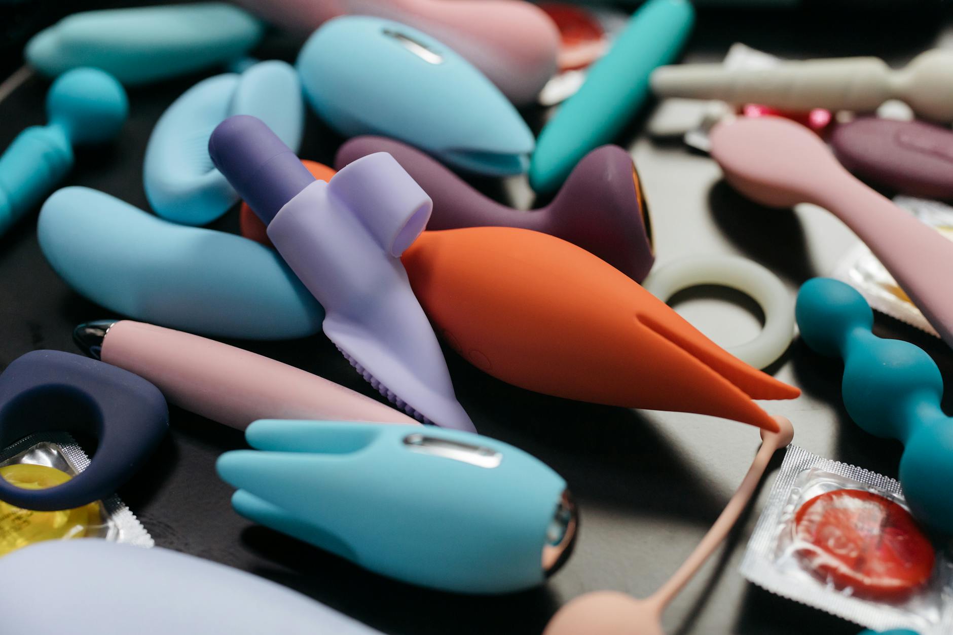 Close-up of a hand holding a pink vibrator with art books in the background