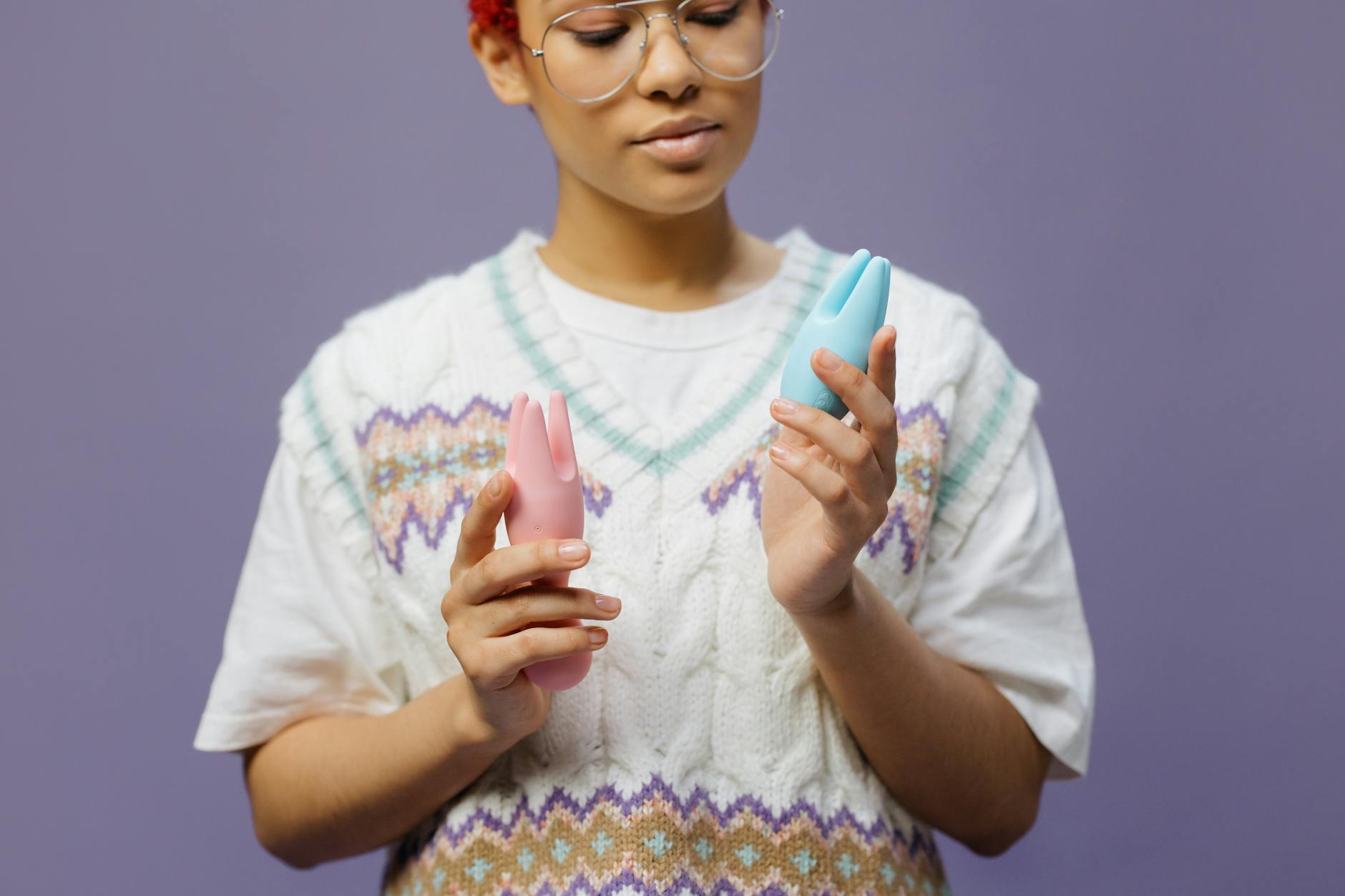 Woman thoughtfully holding a pink silicone vibrator in both hands