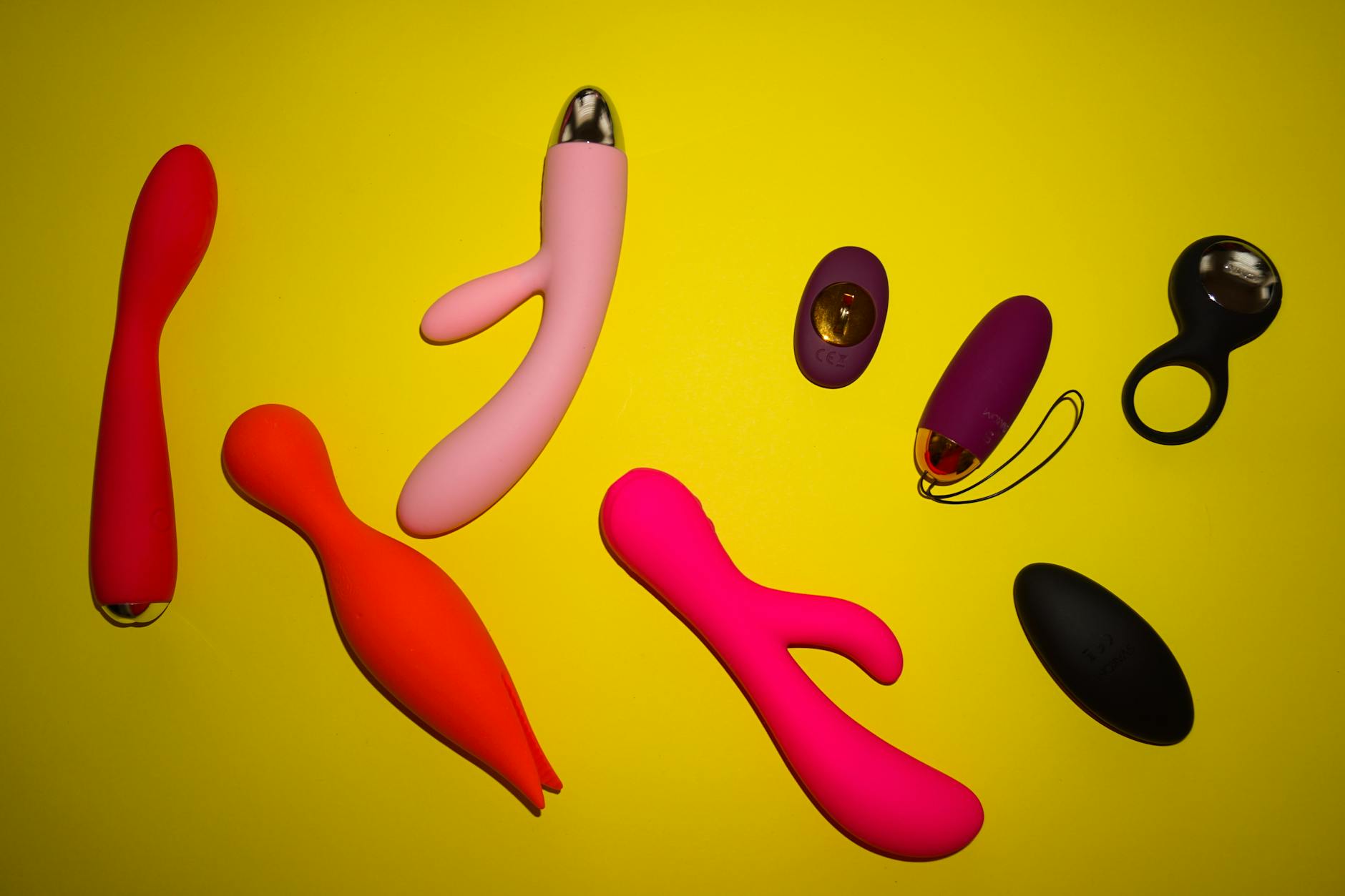 Various colorful vibrators and intimate wellness devices arranged on a bright surface