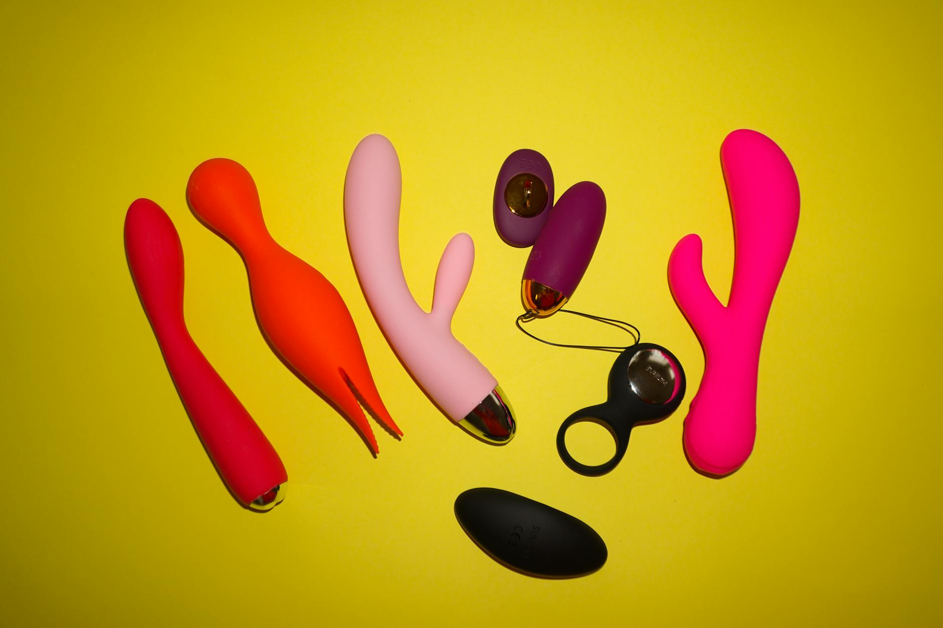 Yellow silicone vibrator surrounded by peeled bananas on yellow background