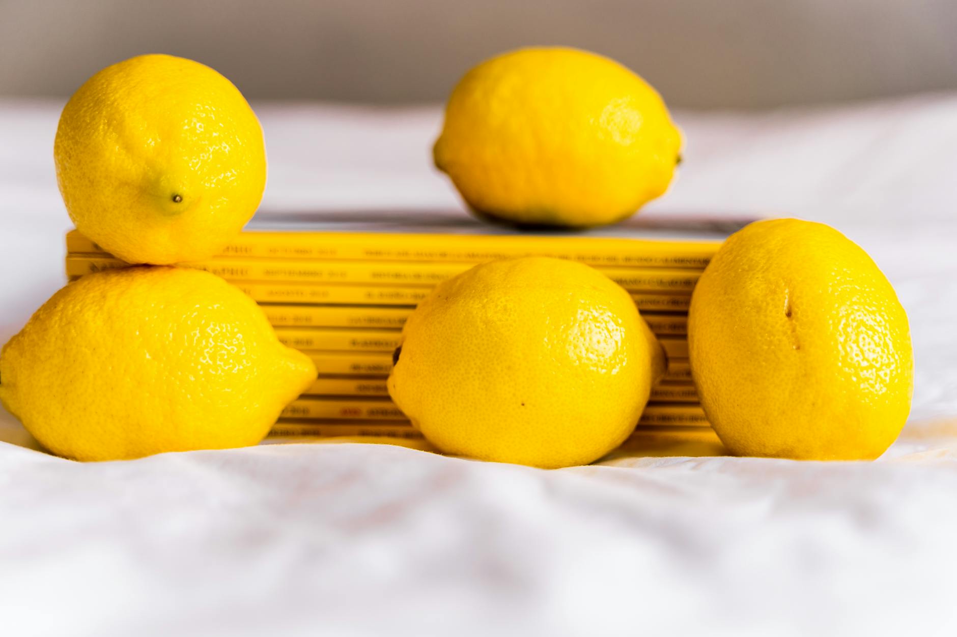 A hand holding a fresh lemon against a vibrant yellow background, symbolizing bright, simple pleasure